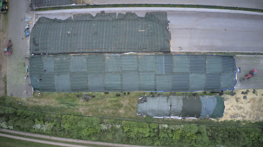 Ein großer Fahrsilo, der mit Vlies und Vogelschutzgitter in einem Schachbrettmuster abgedeckt wurde.